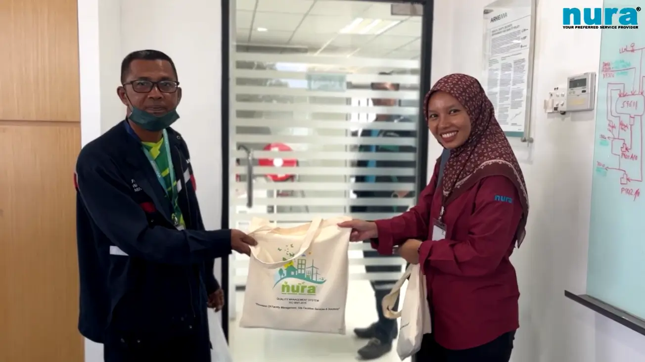 Arkema Malaysia procurement executive receiving NURA-branded tote bag, showcasing NURA's trusted desludging and portable toilet rental services for industrial sanitation.